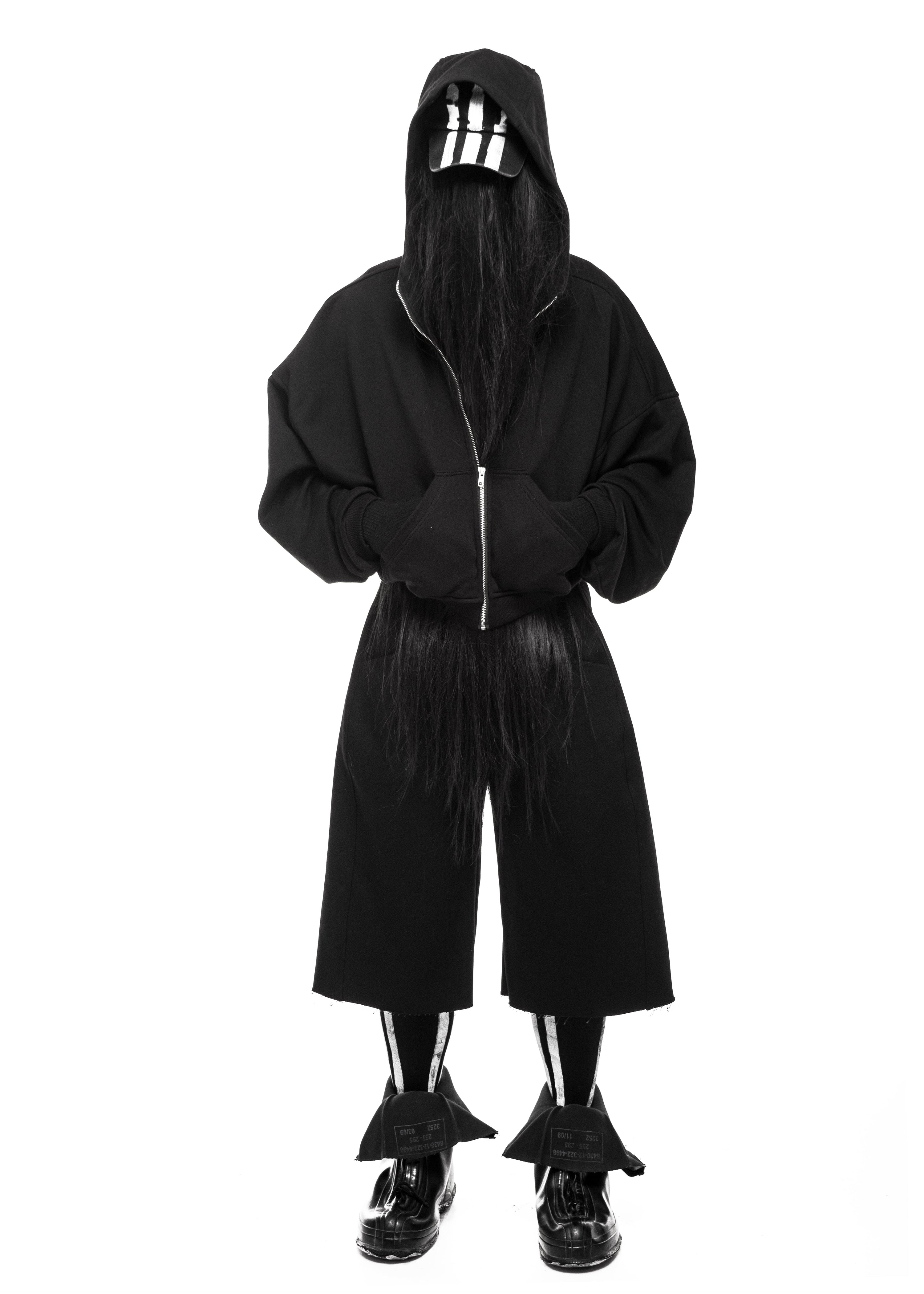 Front view of model wearing black raw denim shorts and hooded jacket, full outfit.