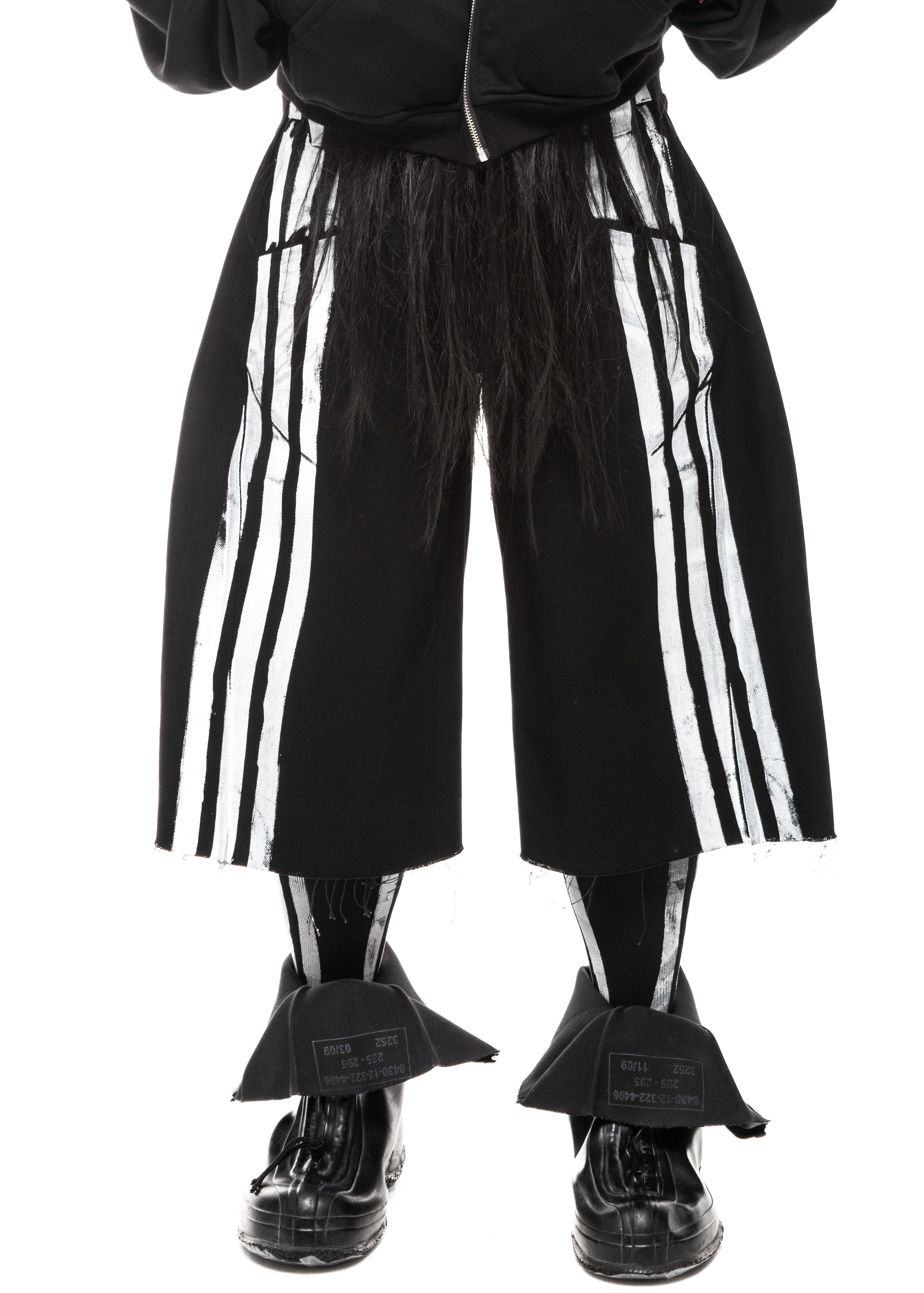 Close-up front view of black denim shorts with white vertical stripes and raw cut hem.