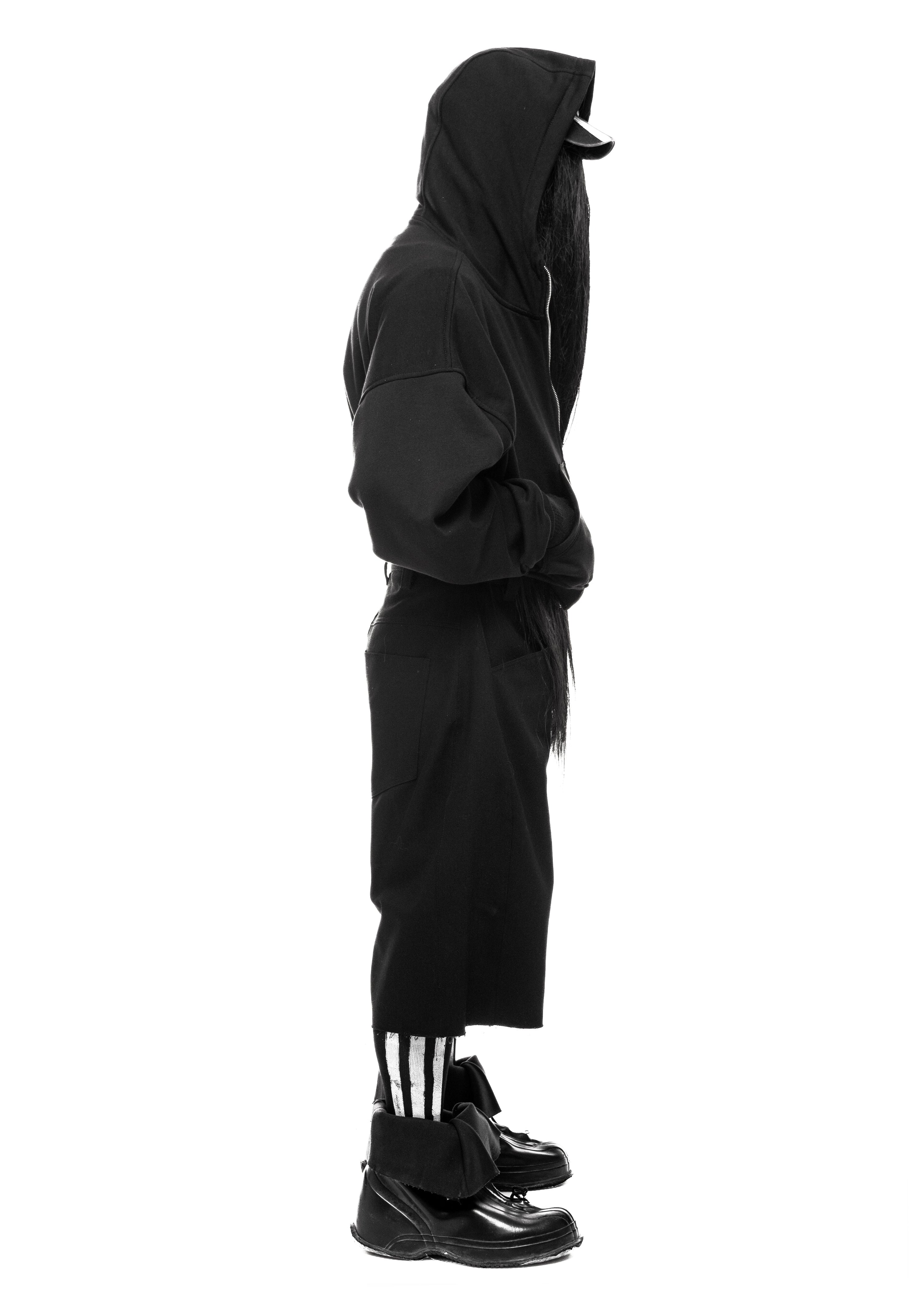 Side view of black denim shorts on model in standing pose.