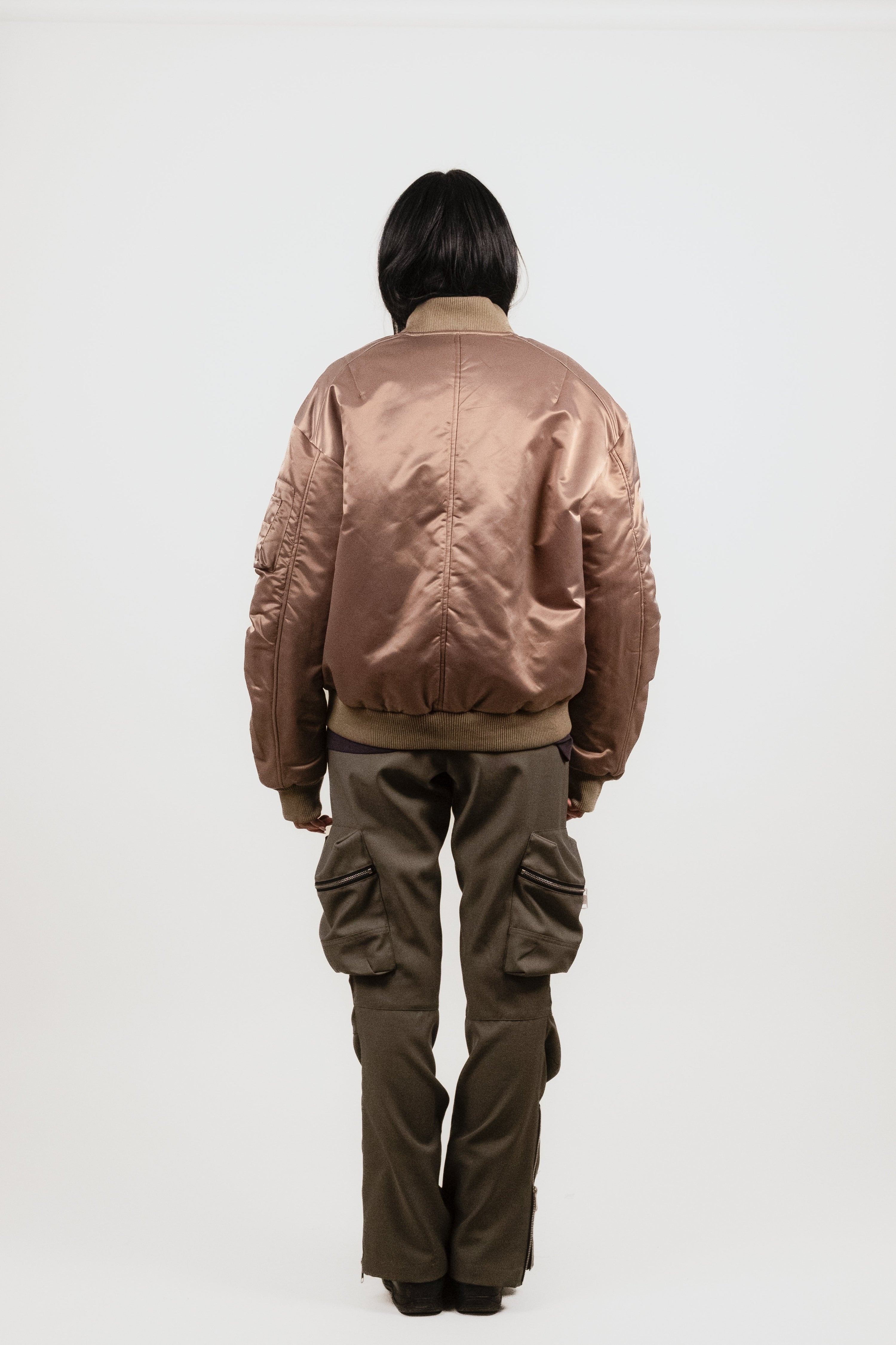 Back view of Anisa in the Ruched Bomber Jacket — slightly oversized olive nylon bomber with luxe fabric drape and heavy rib details.