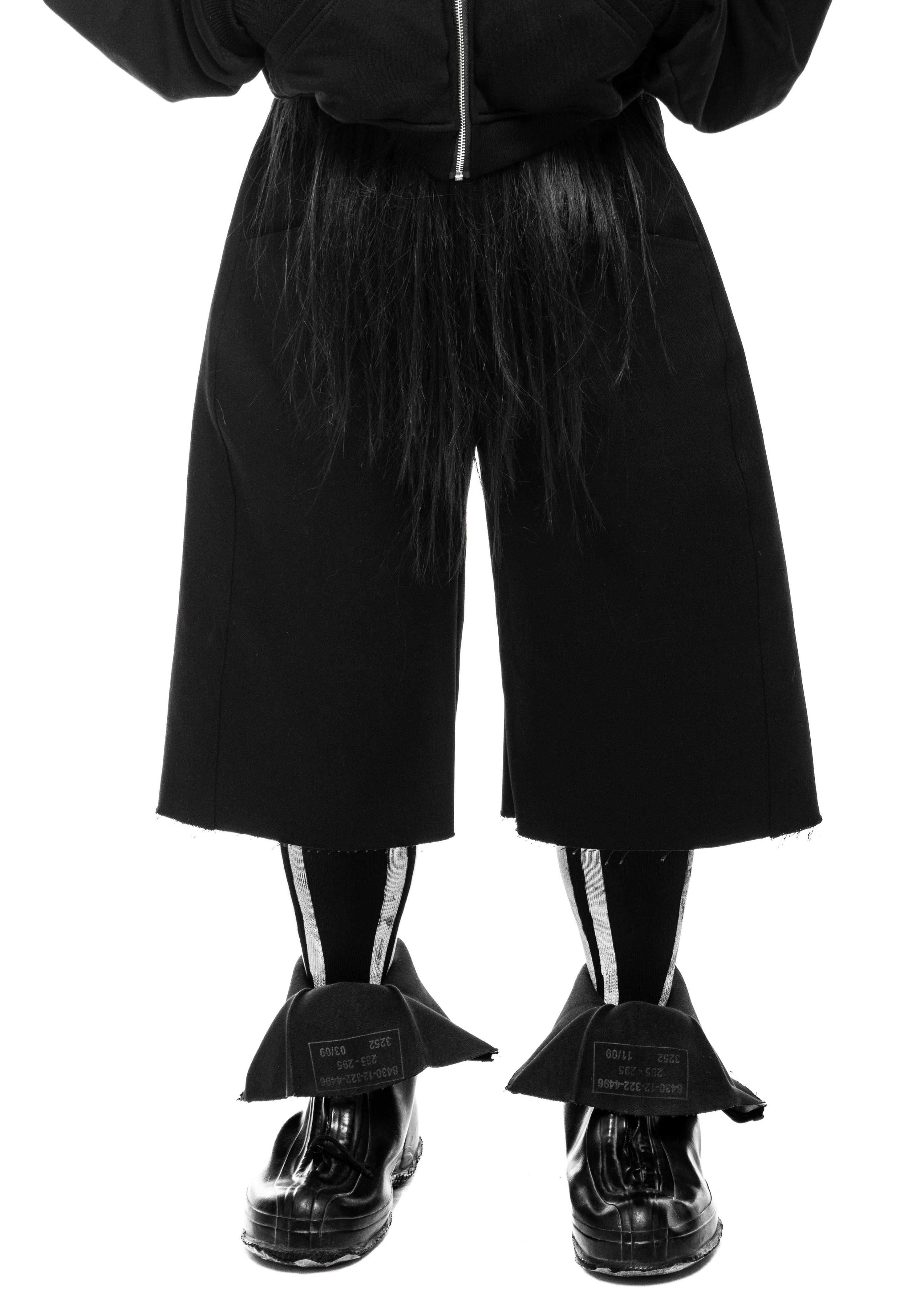 Standing model in frontal pose with layered outerwear and shorts.